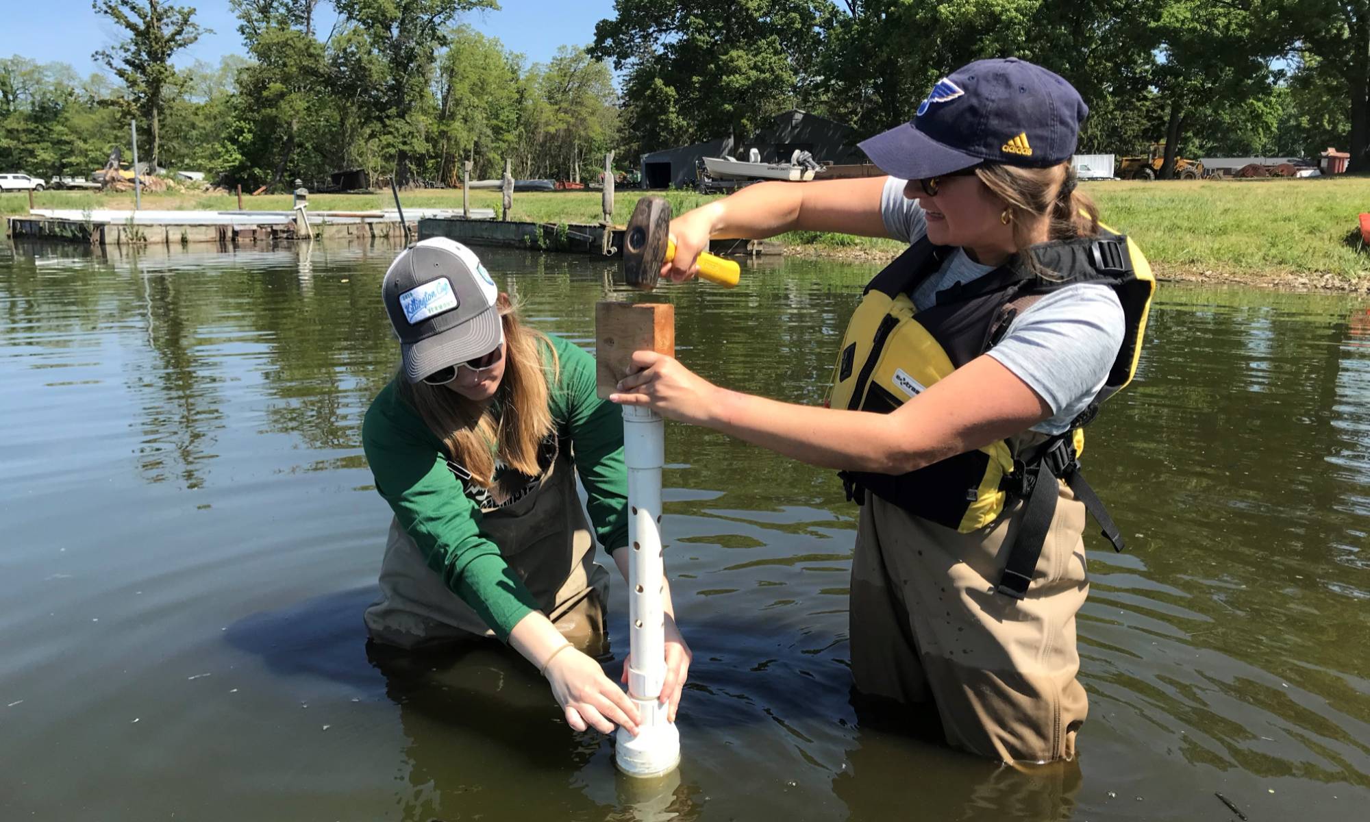 Two technicians collect a sediment core for the Mona Lake celery flat pre-restoration monitoring study.